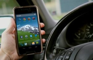 Person holding a cell phone behind the wheel of a car