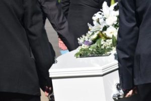 men in black suit holding a coffin 