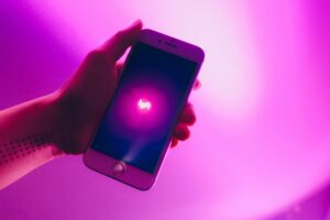 Hand holding a phone with a Lyft logo, surrounded by a pink light
