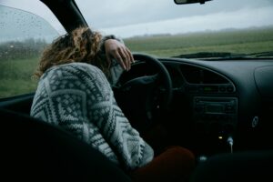 Woman slumped over tired in her car