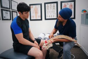 Man in a doctor's office showing another man a diagram of a spinal cord