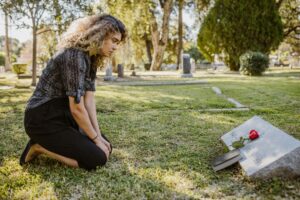 Woman kneeling at a gravesite