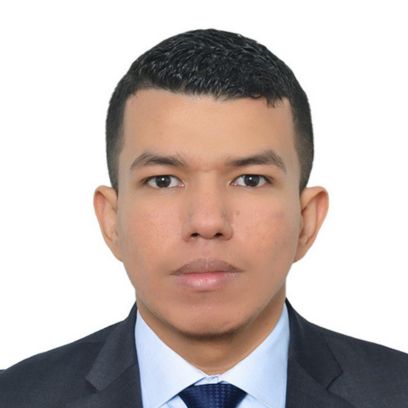 Young man with short dark hair, wearing a suit and tie, against a plain white background.