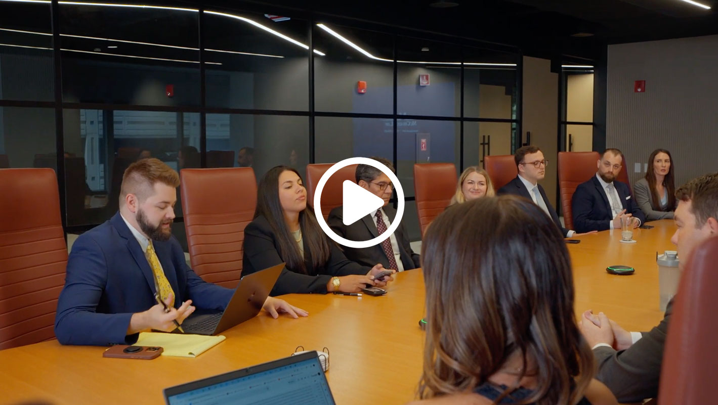 A diverse group of professionals in a conference room, engaged in discussion around a wooden table.