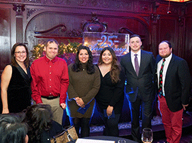 Group of six people smiling at a celebration, with a 