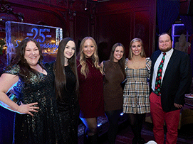 Six people pose together at a celebration, with a 