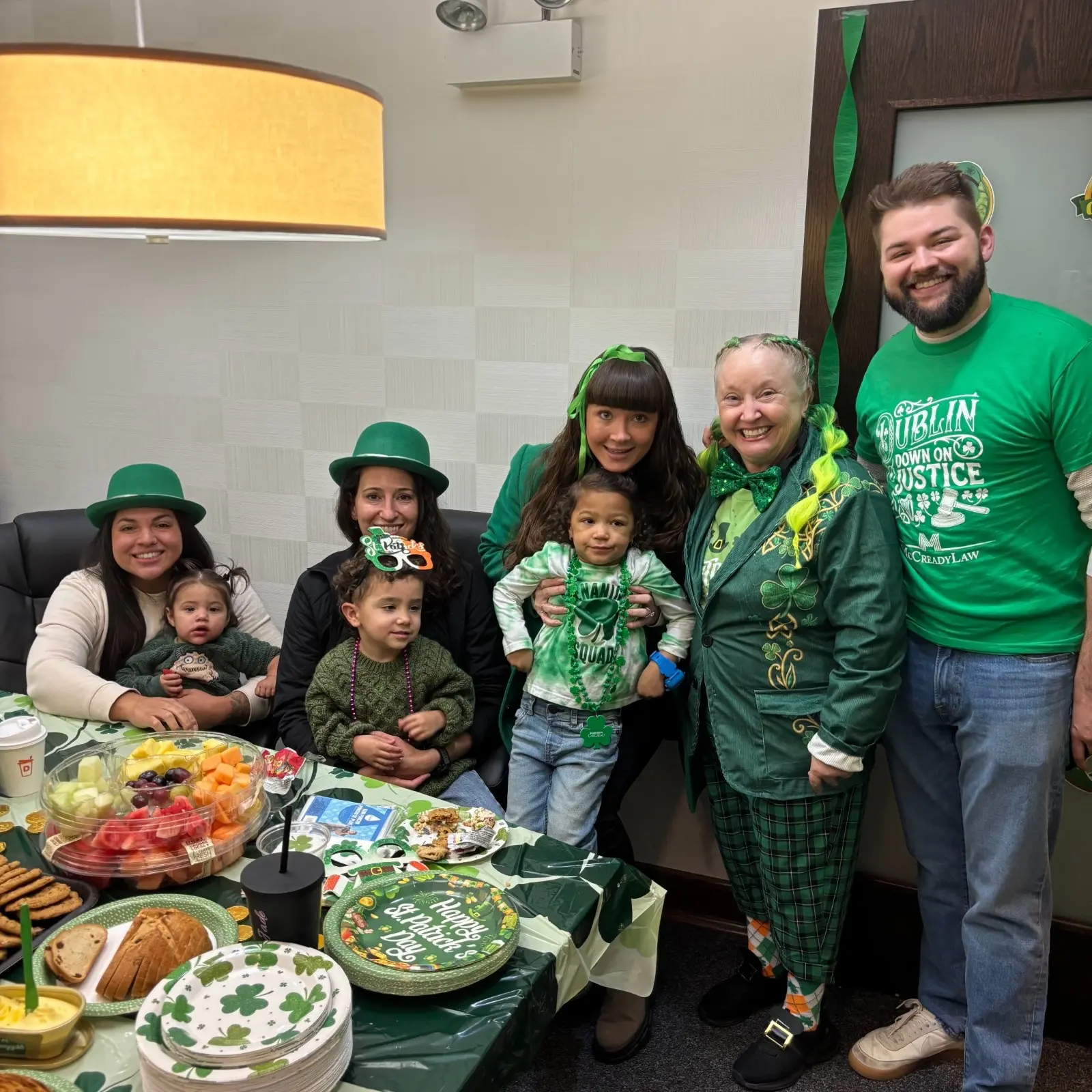 Group of people in green attire celebrating with food and decorations for St. Patrick's Day.