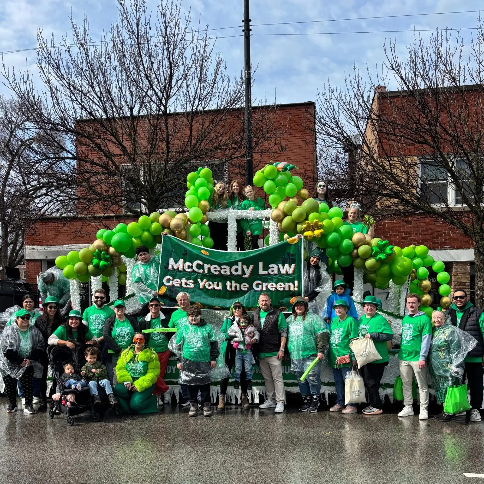 Group of people in green attire with a banner reading "McCready Law Gets You the Green!" at a parade float.